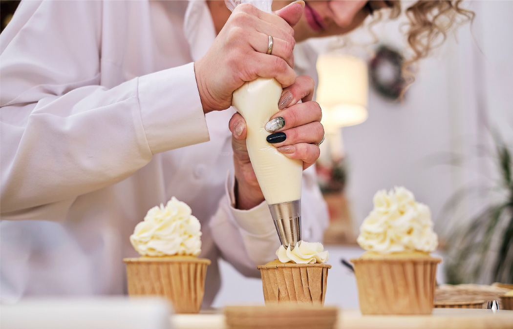 a woman decorating cupcakes with cream