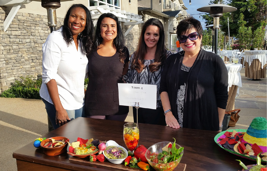 a group of women standing next to a table with food